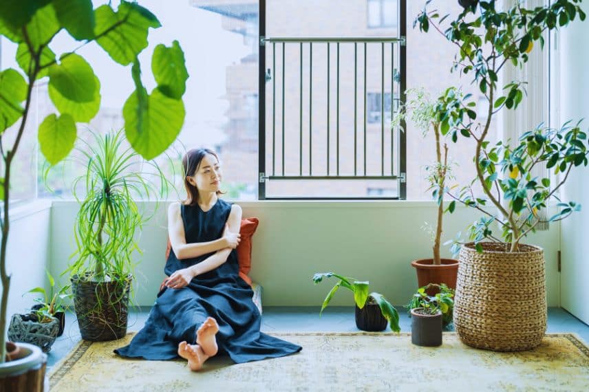 une femme semble détendu, assise aux milieu de ses plantes